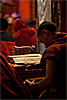 Cushion & Text Photo: A young Tibetan monk breaks from his chants to organize his prayer sheets.