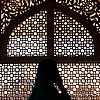 Window Dressing Photo: A Muslim woman walks in front of an intricately carved lattice window.