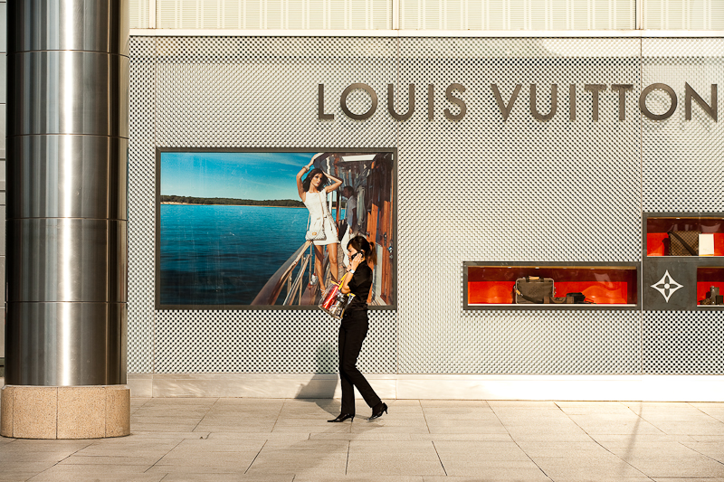 An ethnic Chinese-Malaysian woman walks in front of a Louis Vuitton store. - Kuala Lumpur, Malaysia - Daily Travel Photos