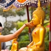 Songkran Buddha Cleansing Photo: A Thai woman at Wat Pho temple rinses a Buddha statue, part of the festival tradition for every Thai new year.
