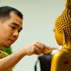 Scented Statue Photo: A Thai man gently pours a small bottle of perfume onto a Buddha statue for Songkran.