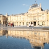 Museum Middle (panorama) Photo: The facade of the Louvre and glass pyramid reflected in a water fountain in the museum's courtyard.