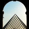 photo: Louvre Leave - People walk through an archway into the courtyard of the Louvre museum. 